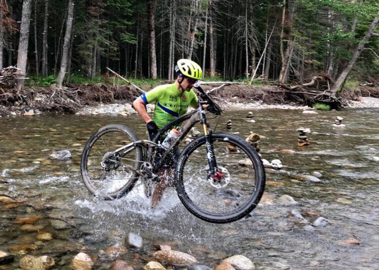 mountain biker having to carry his bike across the river
