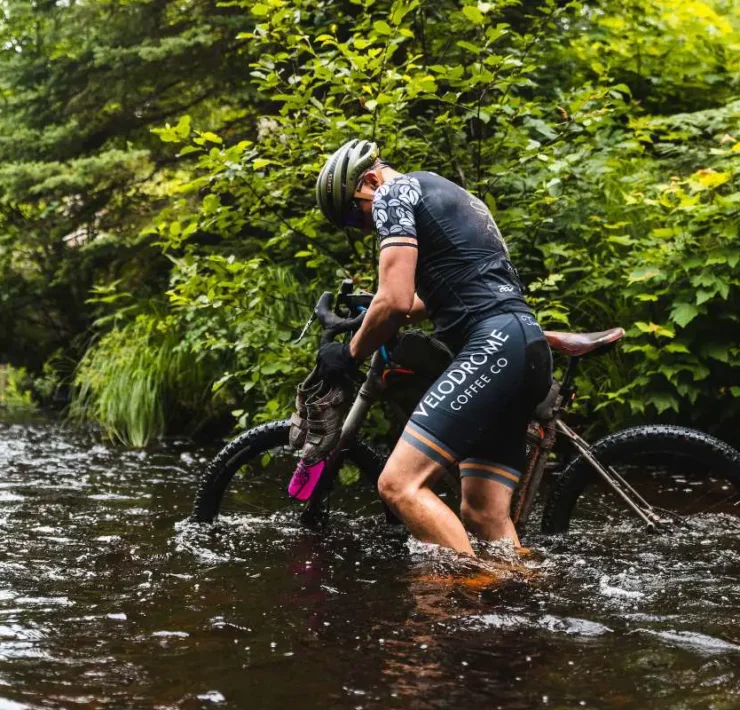 gravel cyclist in water at the crusher event