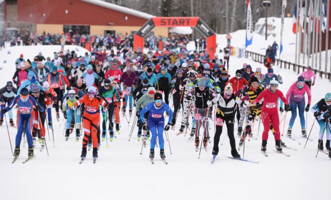 Far away view of women skiing through starting line in seven columns